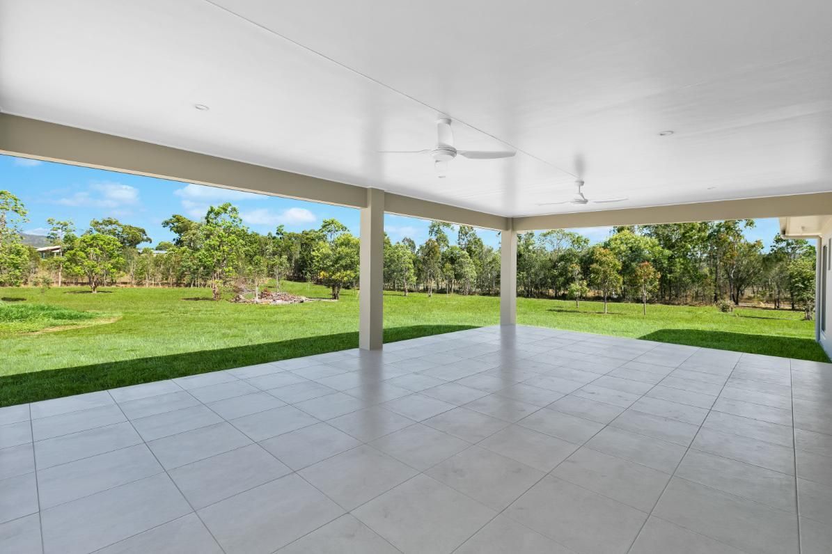 An Empty Patio With a Ceiling Fan and a View of a Grassy Field — Ashlee Jones Homes in Gordonvale, QLD