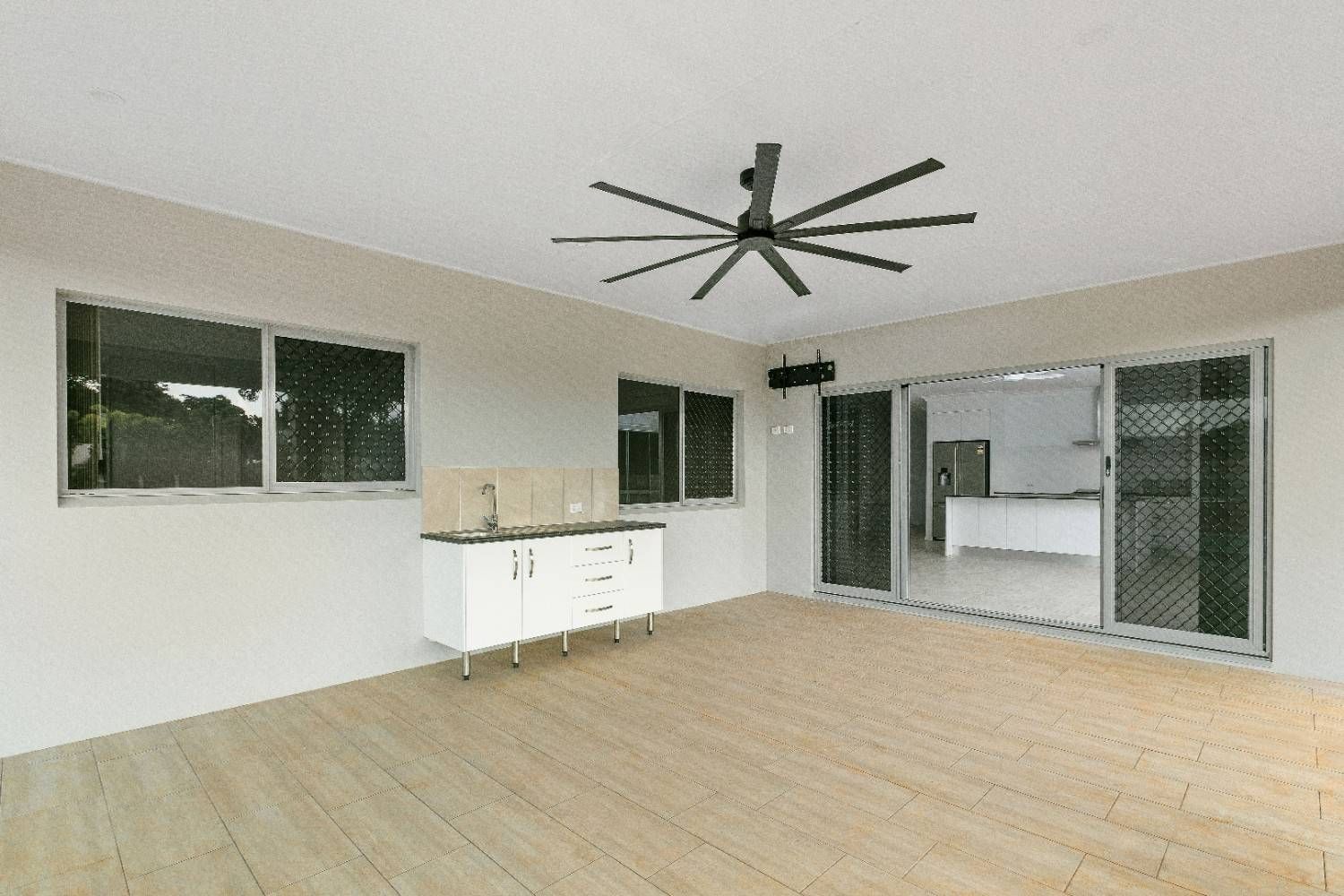 An Empty Room With a Ceiling Fan and Sliding Glass Doors — Ashlee Jones Homes in Gordonvale, QLD