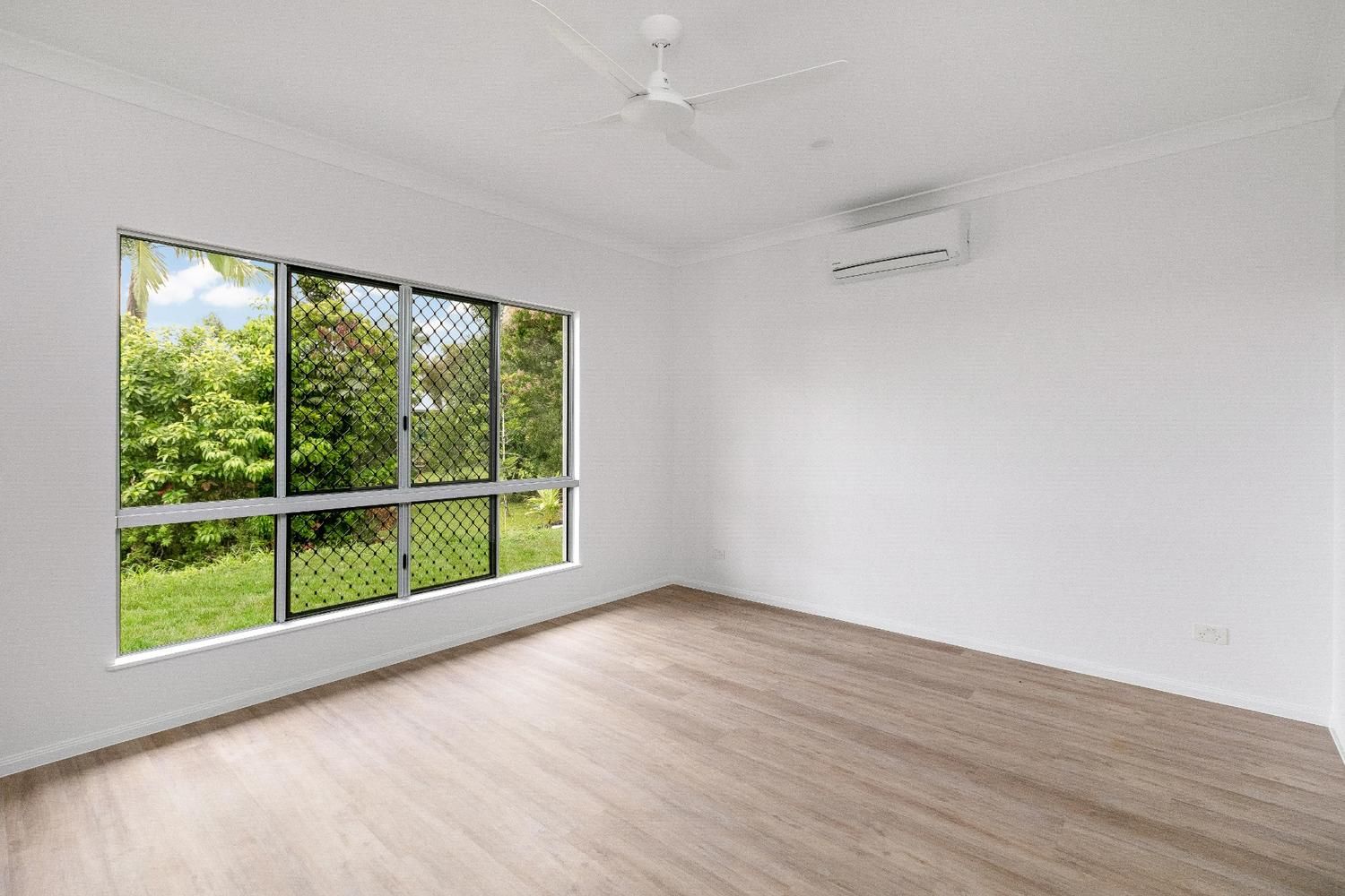 An Empty Room With a Large Window and a Ceiling Fan — Ashlee Jones Homes in Gordonvale, QLD