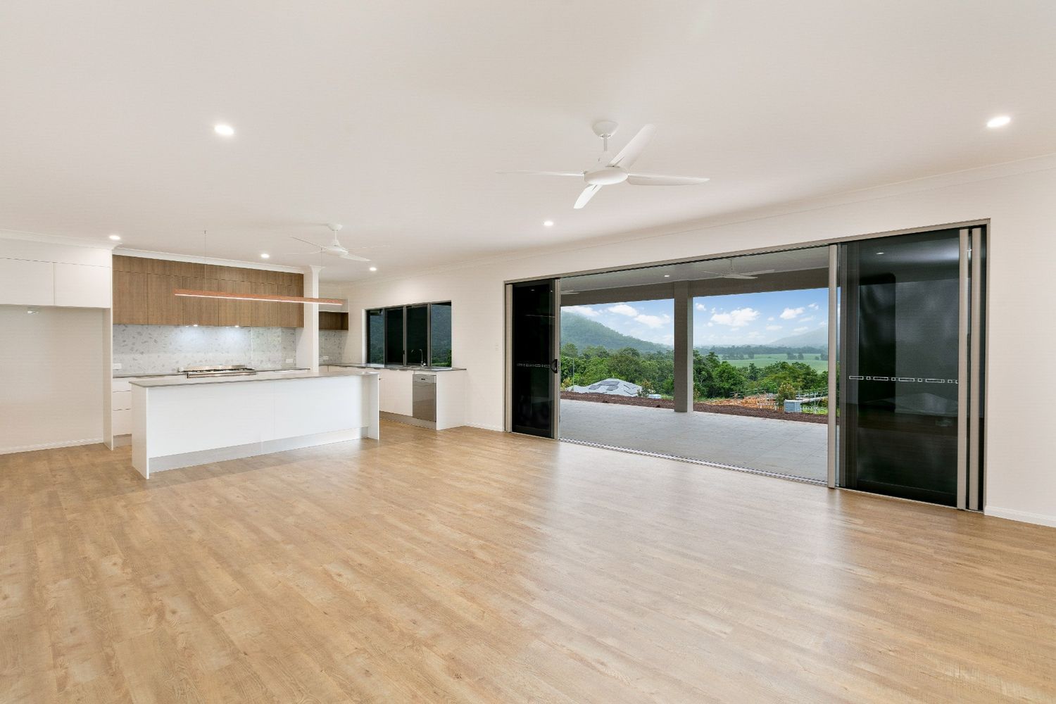 A Large Empty Room With Hardwood Floors and a Ceiling Fan — Ashlee Jones Homes in Gordonvale, QLD