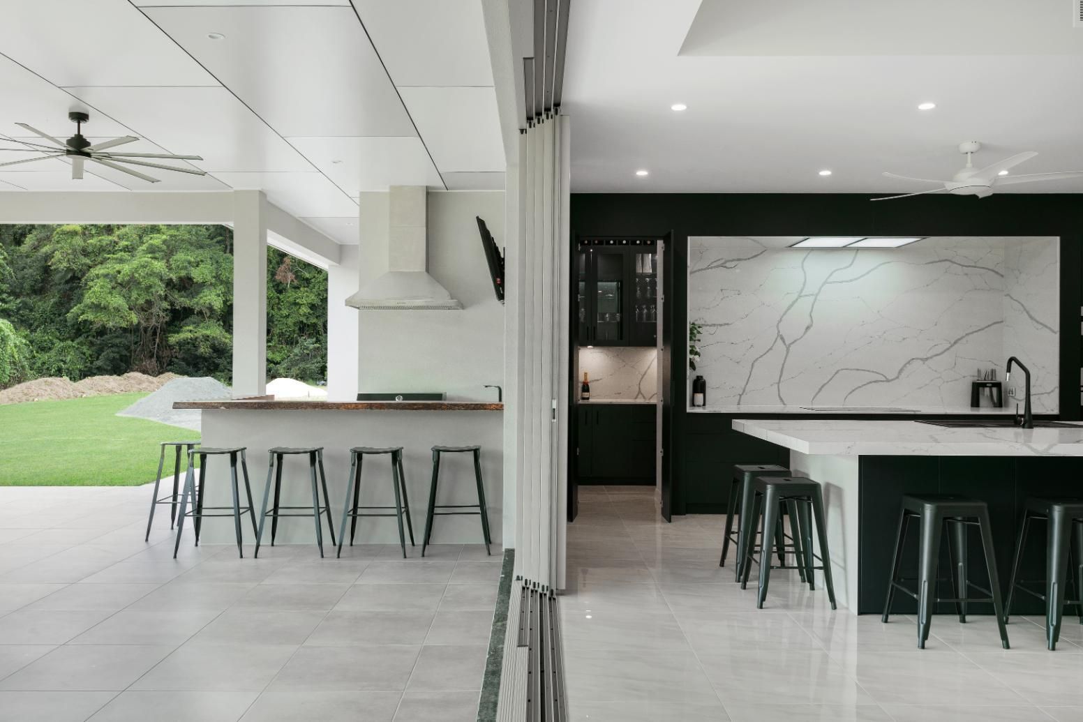 A Kitchen With a Large Island and Stools in It — Ashlee Jones Homes in Gordonvale, QLD