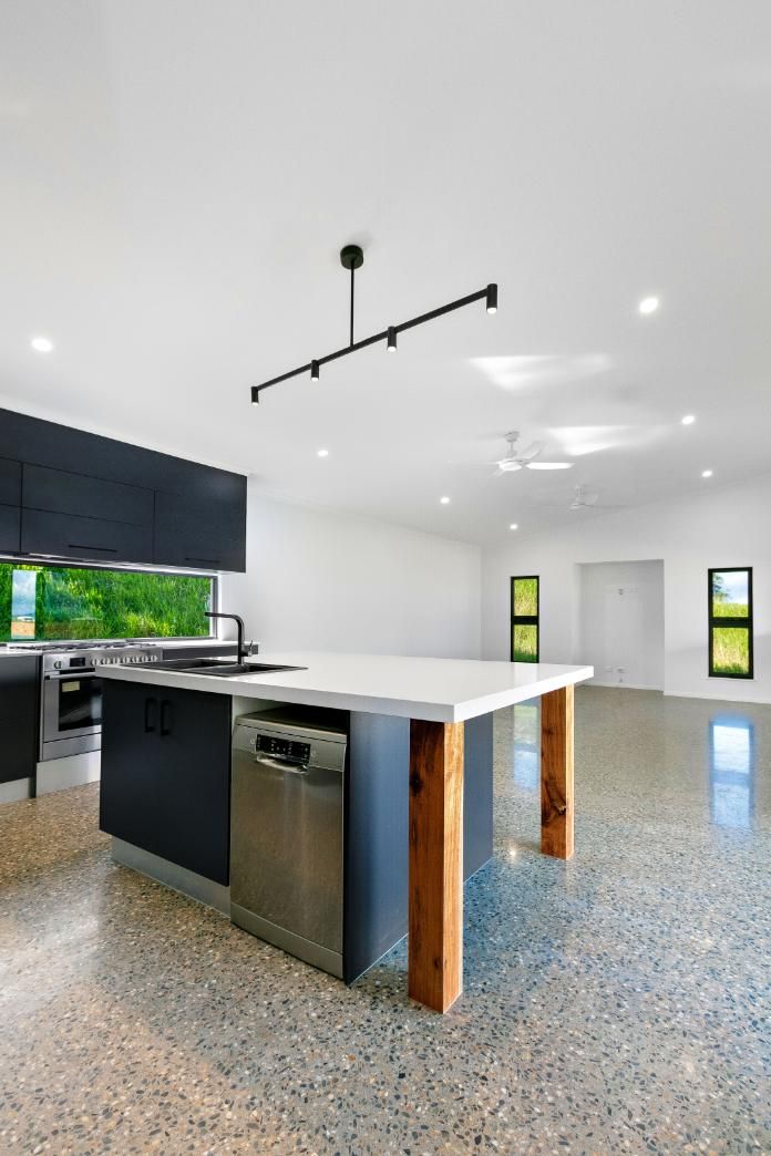 A Kitchen With a Large Island and a Stainless Steel Dishwasher — Ashlee Jones Homes in Gordonvale, QLD
