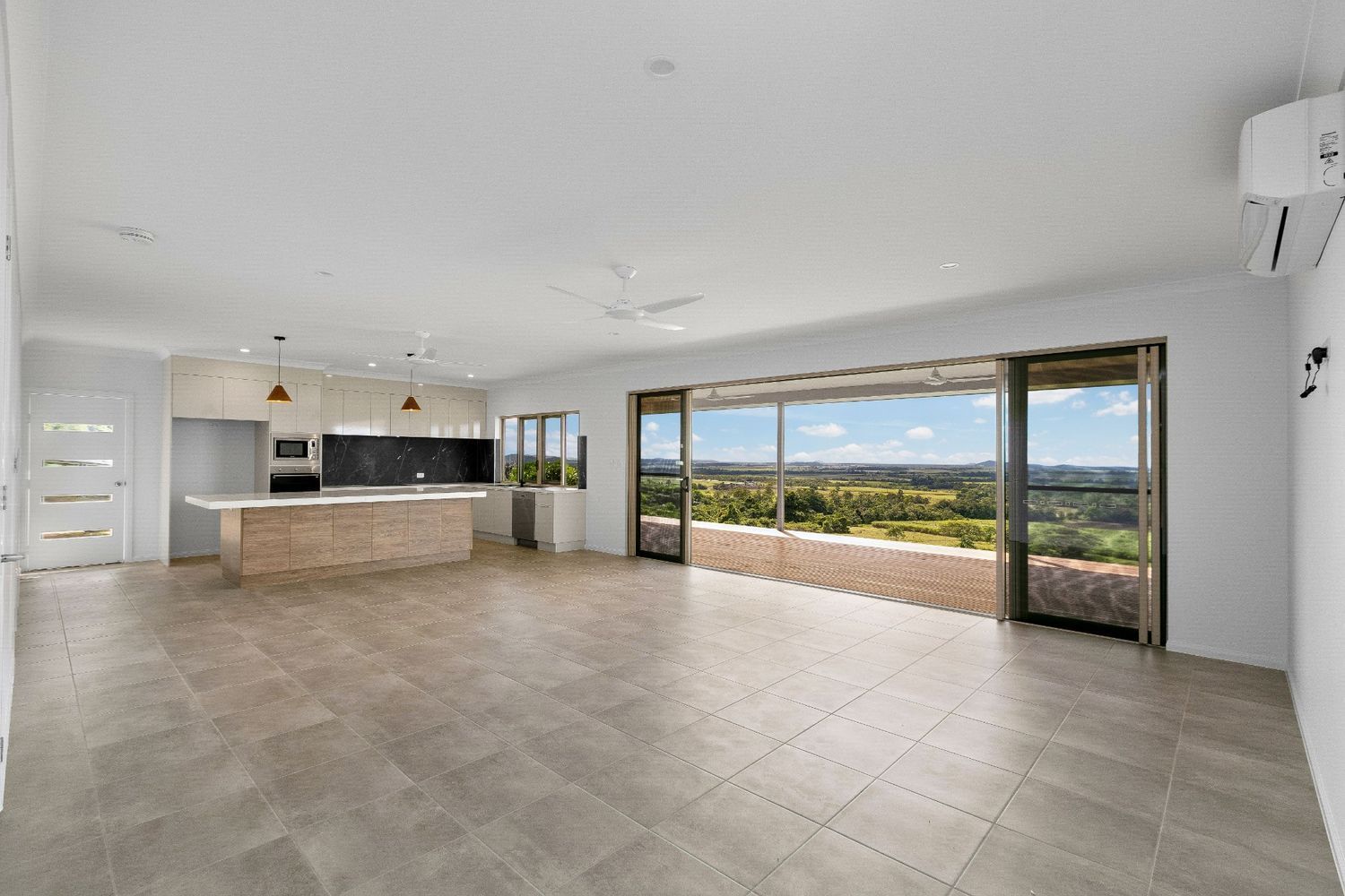 An Empty Living Room With a View of a Valley and a Kitchen — Ashlee Jones Homes in Gordonvale, QLD
