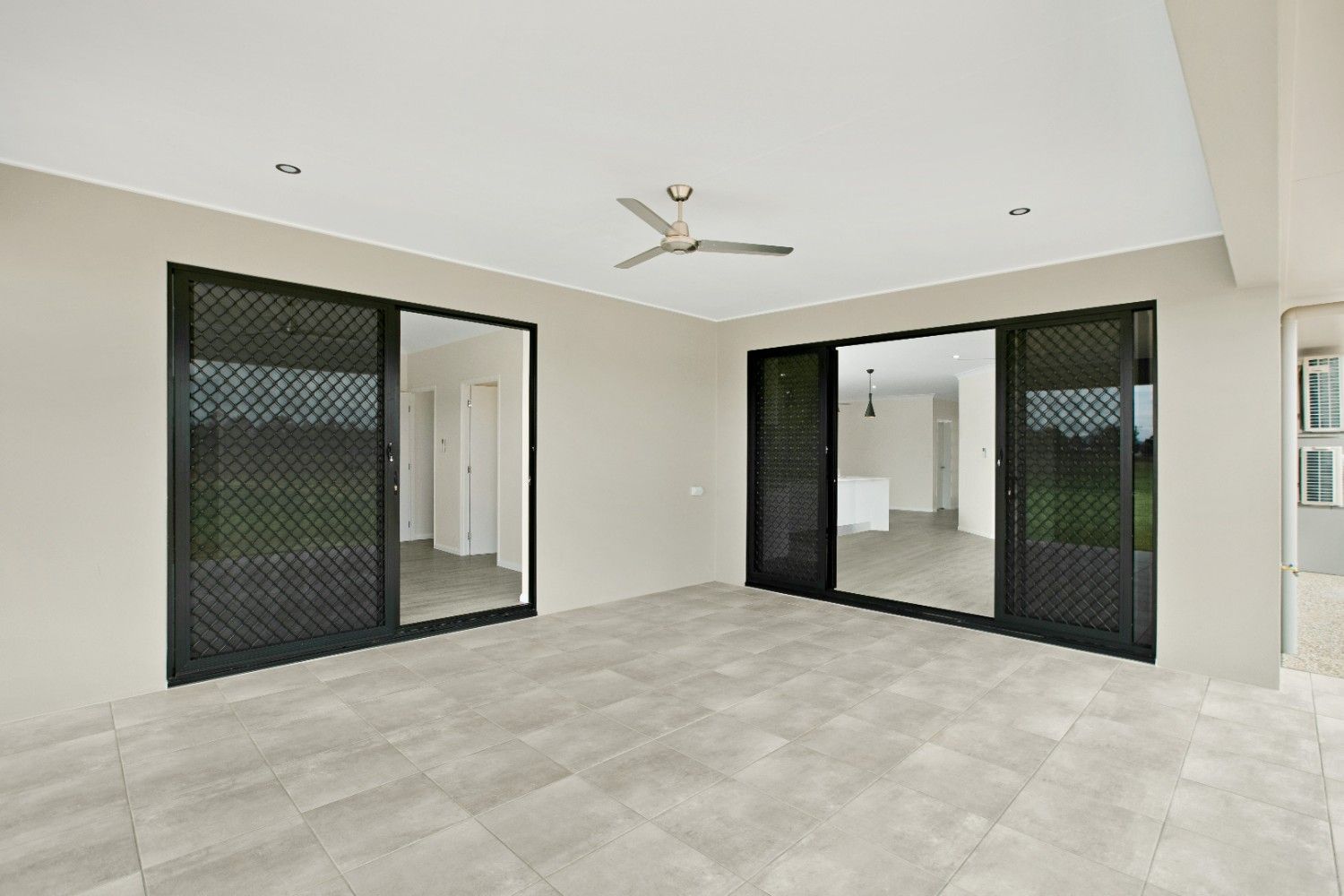 An Empty Room With Sliding Glass Doors and a Ceiling Fan — Ashlee Jones Homes in Gordonvale, QLD