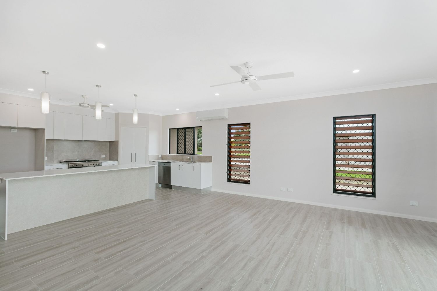 A Large Empty Room With a Kitchen and a Ceiling Fan — Ashlee Jones Homes in Gordonvale, QLD