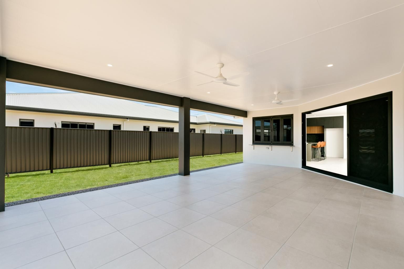 An Empty Patio With a Fence and Sliding Glass Doors Leading to a Kitchen — Ashlee Jones Homes in Gordonvale, QLD
