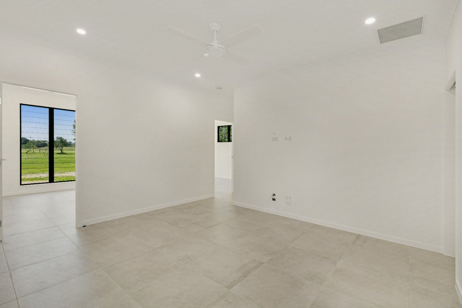 An Empty Living Room With a Large Window and Tile Floor — Ashlee Jones Homes in Gordonvale, QLD