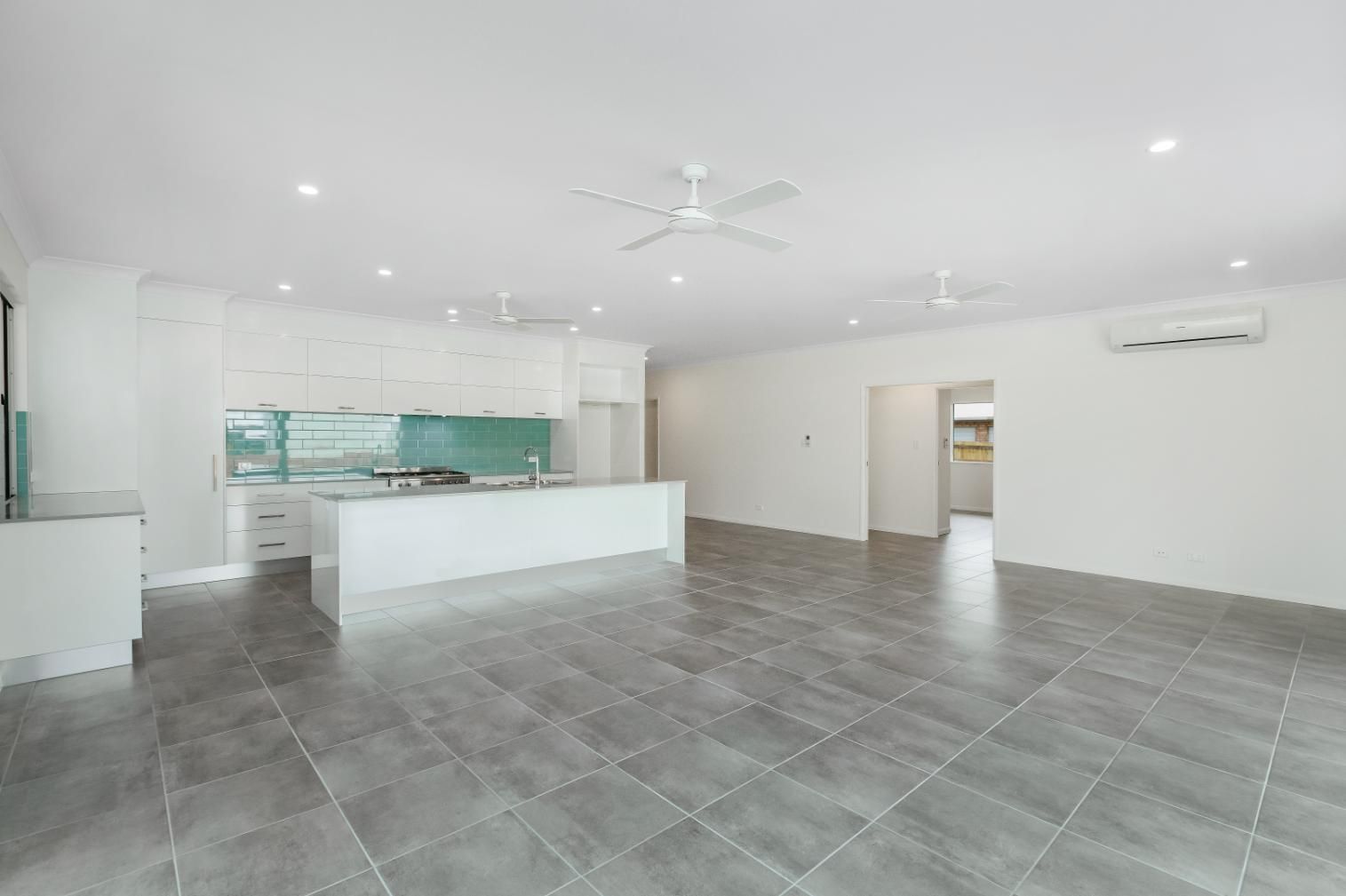 A Large Empty Room With a Kitchen and a Ceiling Fan — Ashlee Jones Homes in Gordonvale, QLD