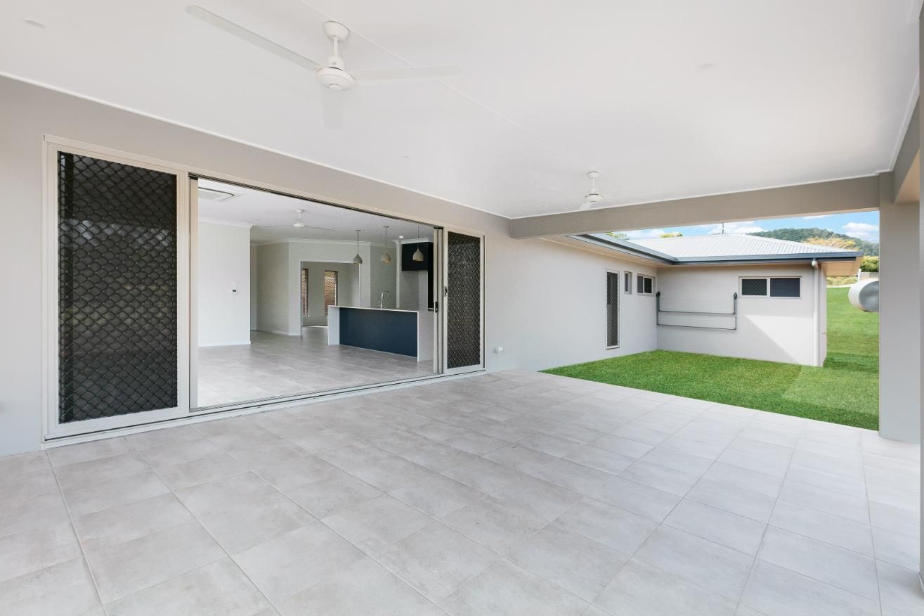 A Large Patio With Sliding Glass Doors and a Ceiling Fan in a House — Ashlee Jones Homes in Gordonvale, QLD