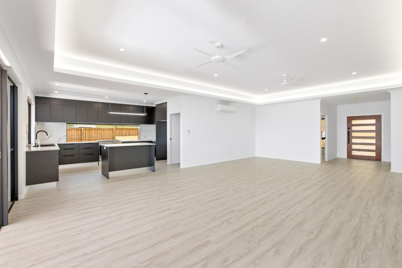 A Large Empty Room With a Kitchen and a Ceiling Fan — Ashlee Jones Homes in Gordonvale, QLD