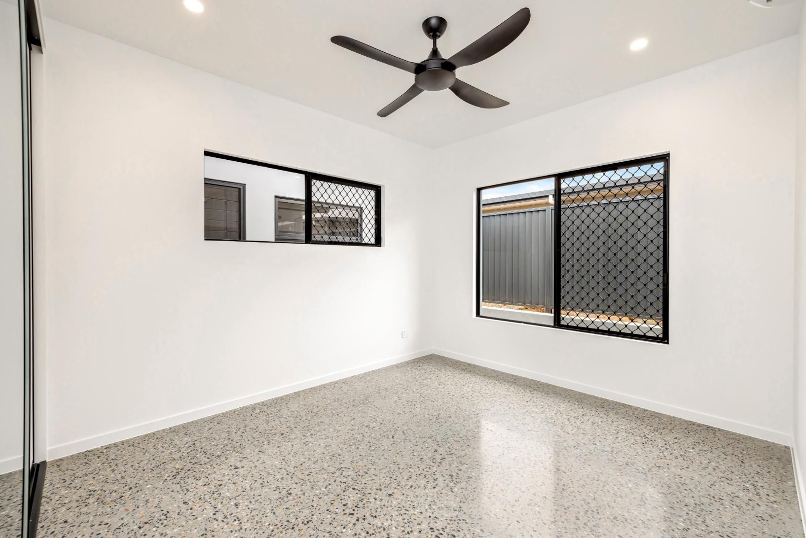 An Empty Room with A Ceiling Fan and Two Windows — Ashlee Jones Homes in Gordonvale, QLD