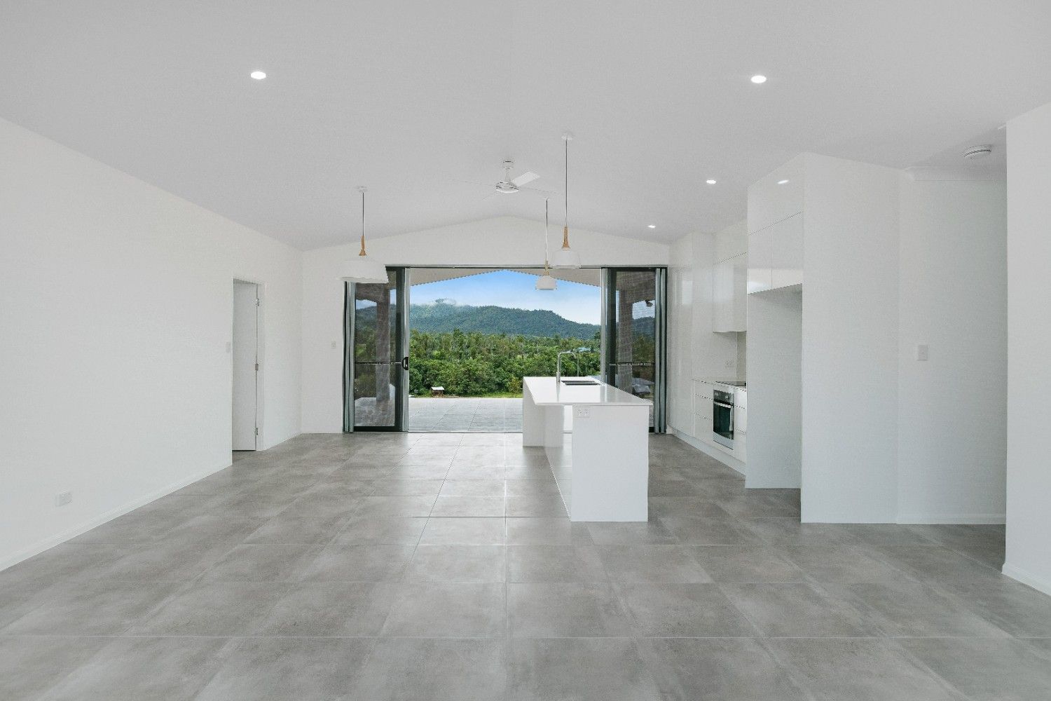A Large Empty Room With a Kitchen and a View of the Mountains — Ashlee Jones Homes in Gordonvale, QLD