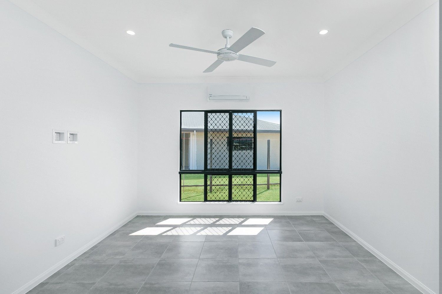 An Empty Room With a Ceiling Fan and a Window — Ashlee Jones Homes in Gordonvale, QLD