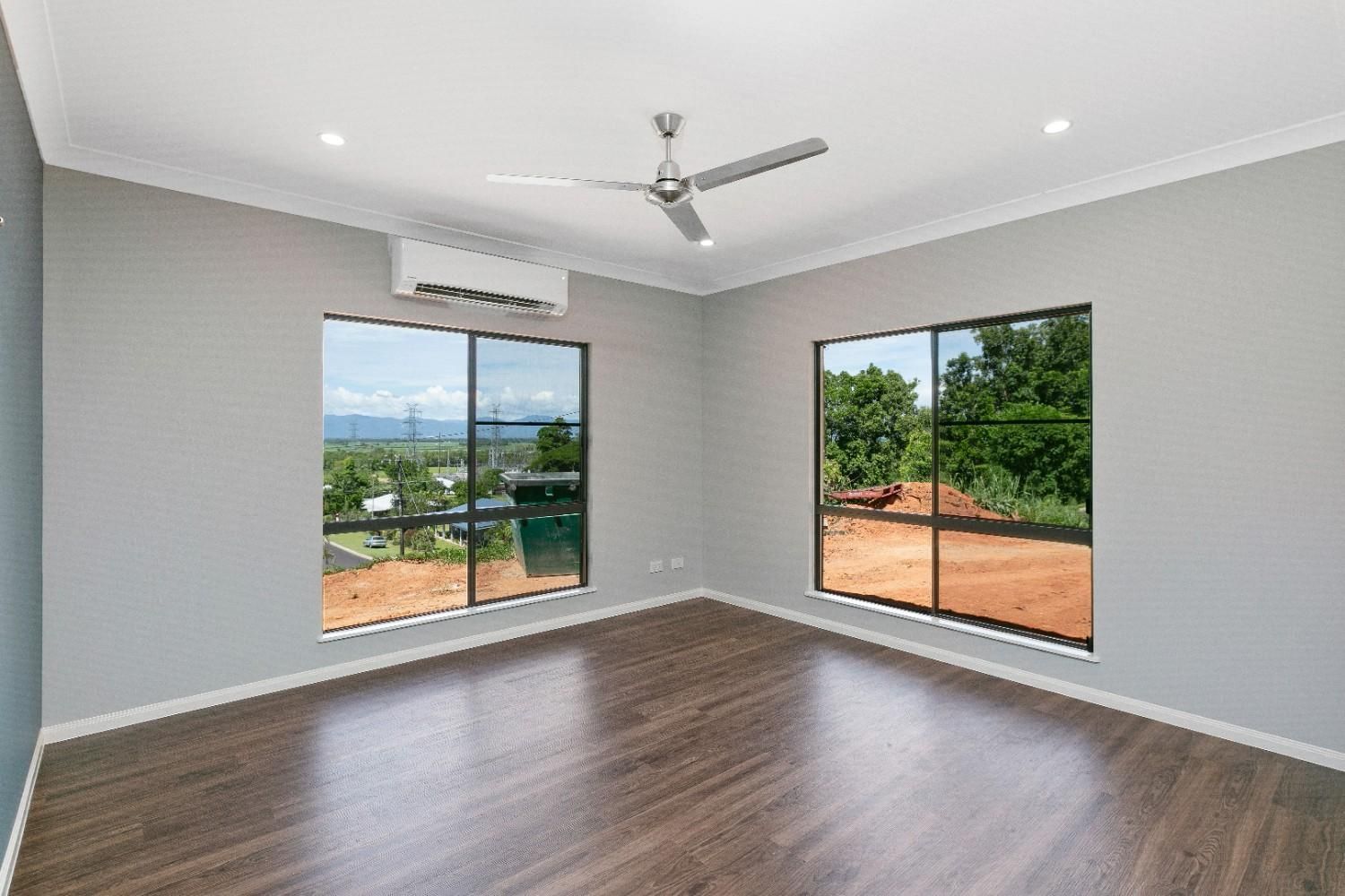 An Empty Room With a Ceiling Fan and Two Windows — Ashlee Jones Homes in Gordonvale, QLD