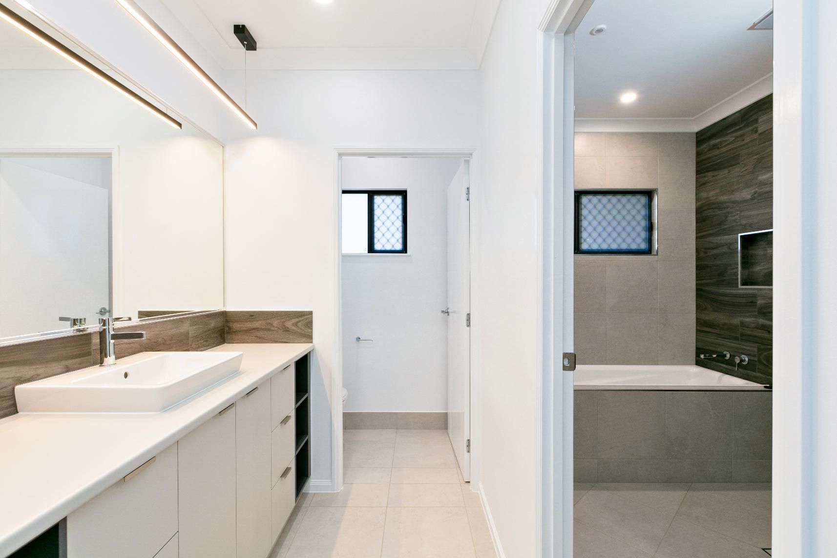 A Bathroom With a Sink, Mirror and Tub — Ashlee Jones Homes in Gordonvale, QLD