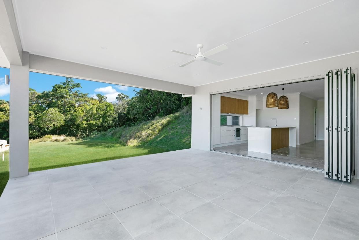 An Empty Patio With a Ceiling Fan and Sliding Glass Doors Leading to a Kitchen — Ashlee Jones Homes in Gordonvale, QLD