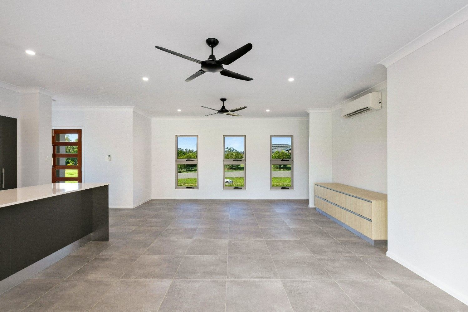 An Empty Living Room With a Ceiling Fan and a Lot of Windows — Ashlee Jones Homes in Gordonvale, QLD