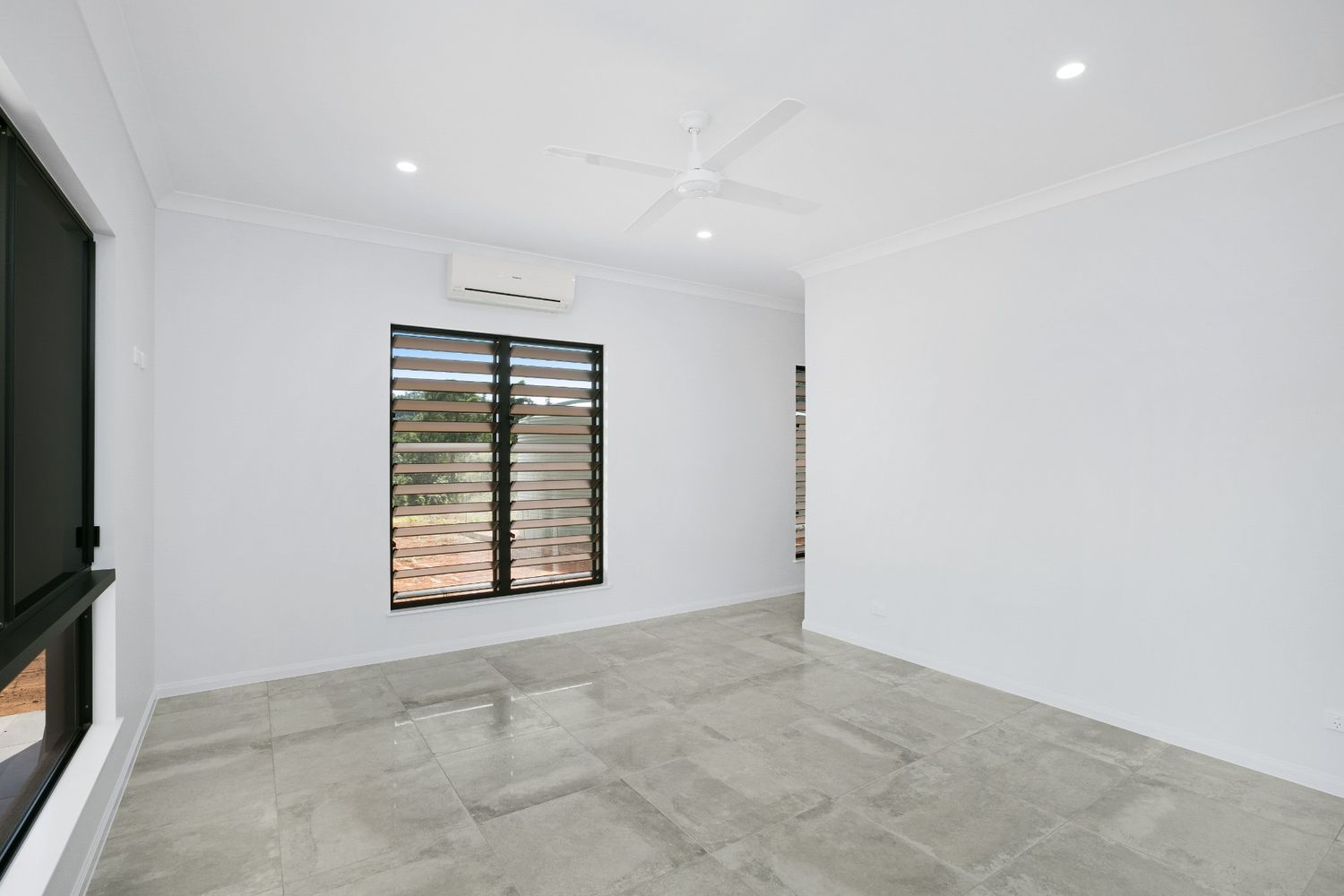 An Empty Room With a Ceiling Fan and Two Windows — Ashlee Jones Homes in Gordonvale, QLD