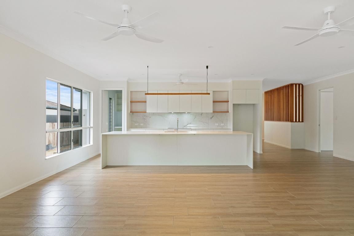 A Large Empty Room With a Kitchen and a Ceiling Fan— Ashlee Jones Homes in Gordonvale, QLD