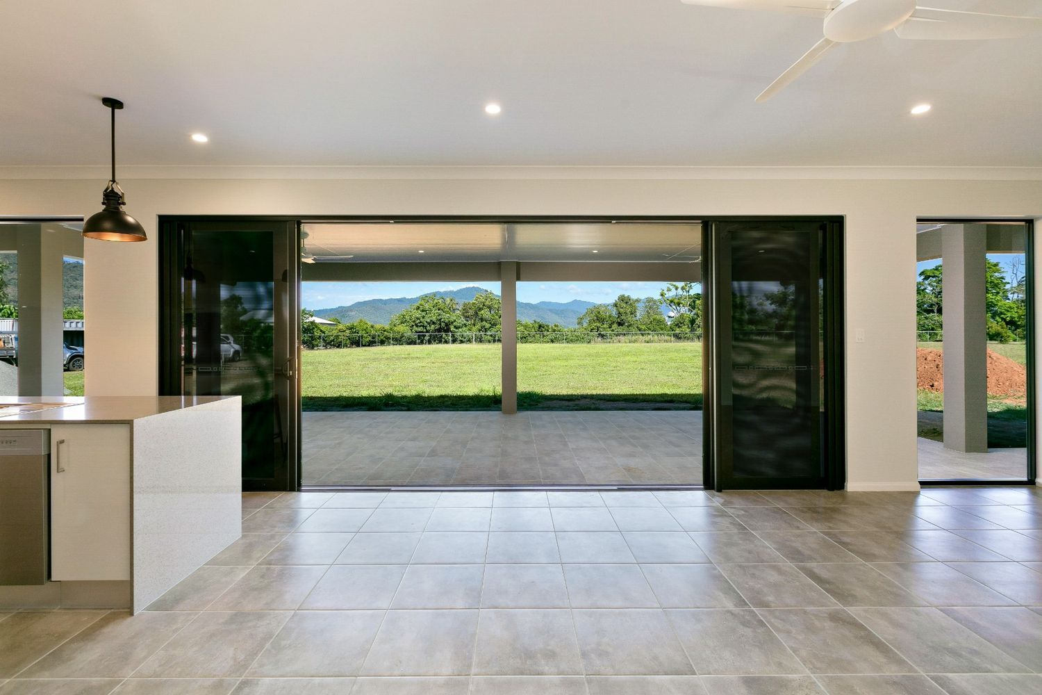 An Empty Kitchen With a Large Sliding Glass Door — Ashlee Jones Homes in Gordonvale, QLD