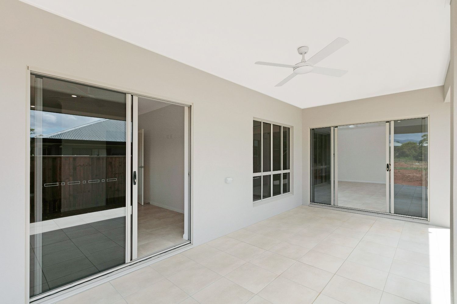 An Empty Room With Sliding Glass Doors and a Ceiling Fan — Ashlee Jones Homes in Gordonvale, QLD