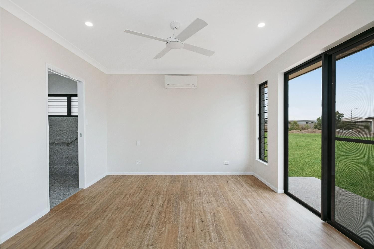 An Empty Room With Hardwood Floors and a Ceiling Fan — Ashlee Jones Homes in Gordonvale, QLD
