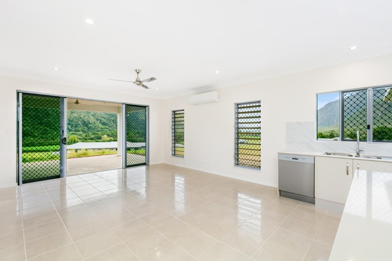 An Empty Living Room With a Kitchen and Sliding Glass Doors Leading to a Patio — Ashlee Jones Homes in Gordonvale, QLD