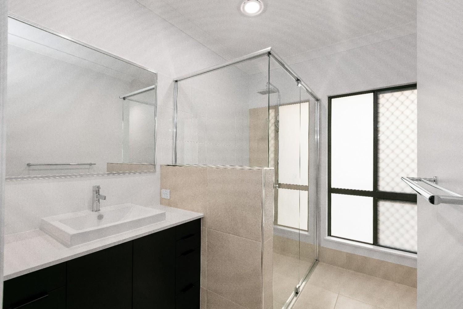 A Bathroom With a Sink, Mirror and Walk in Shower — Ashlee Jones Homes in Gordonvale, QLD