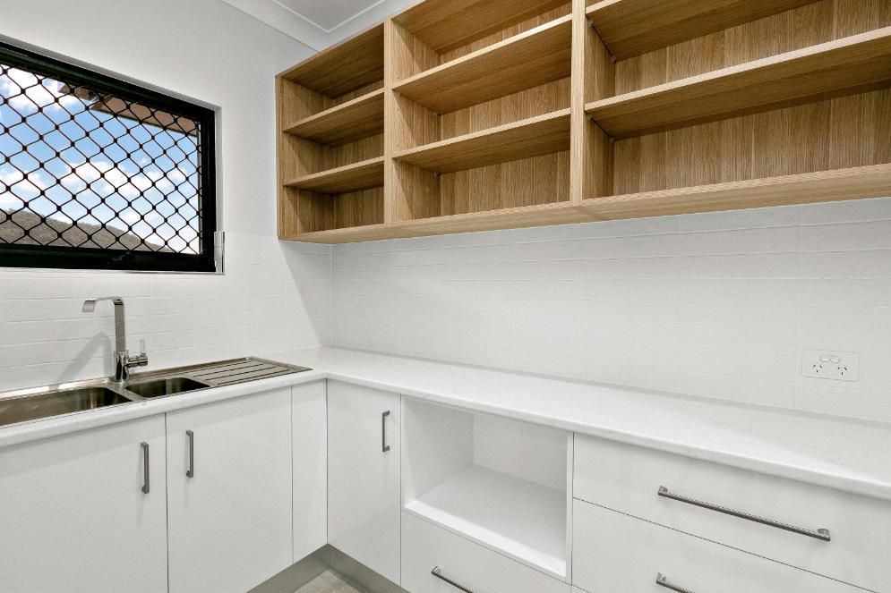A Kitchen With White Cabinets, Wooden Shelves, a Sink and a Window — Ashlee Jones Homes in Gordonvale, QLD