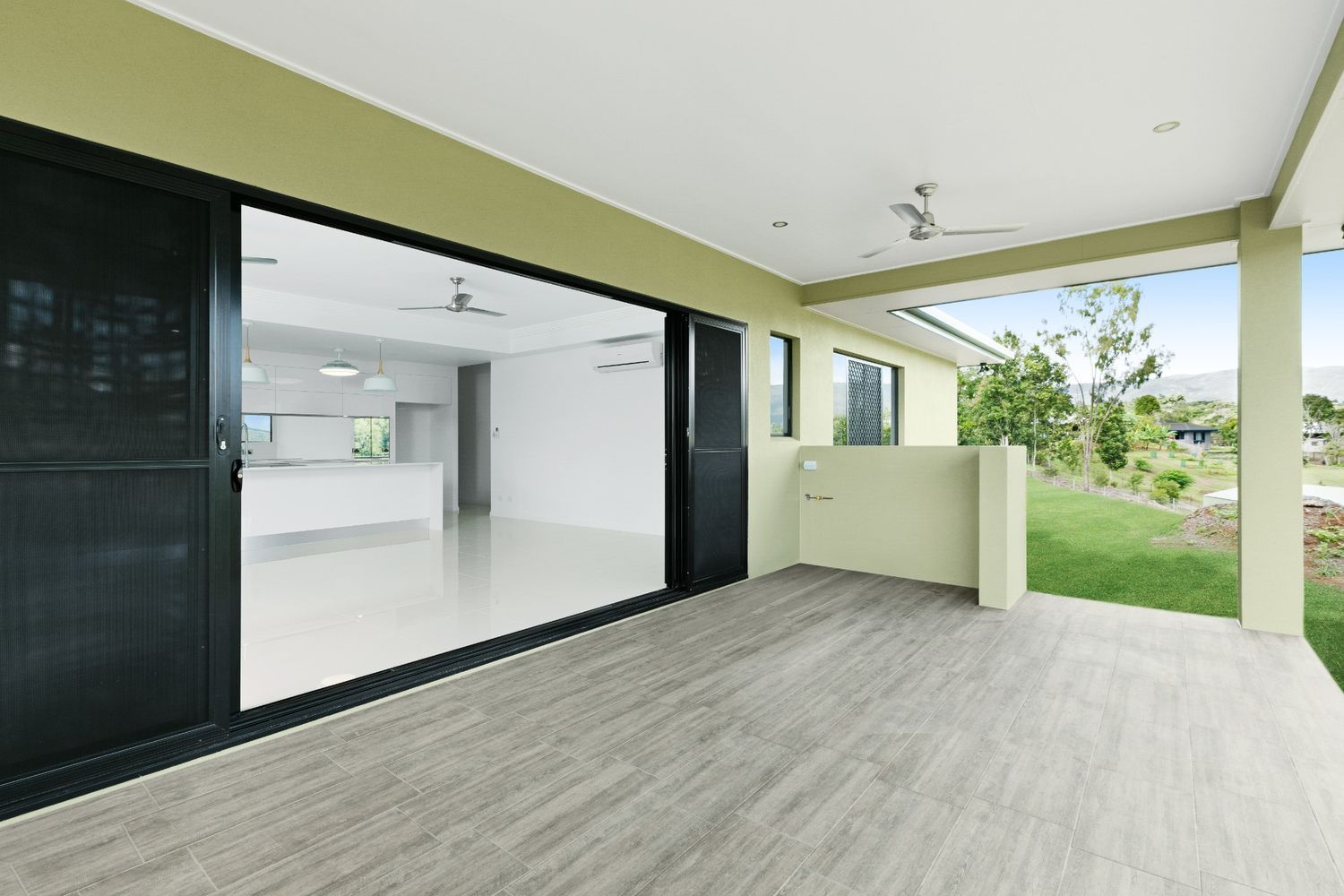 A Large Patio With Sliding Glass Doors and a Ceiling Fan — Ashlee Jones Homes in Gordonvale, QLD