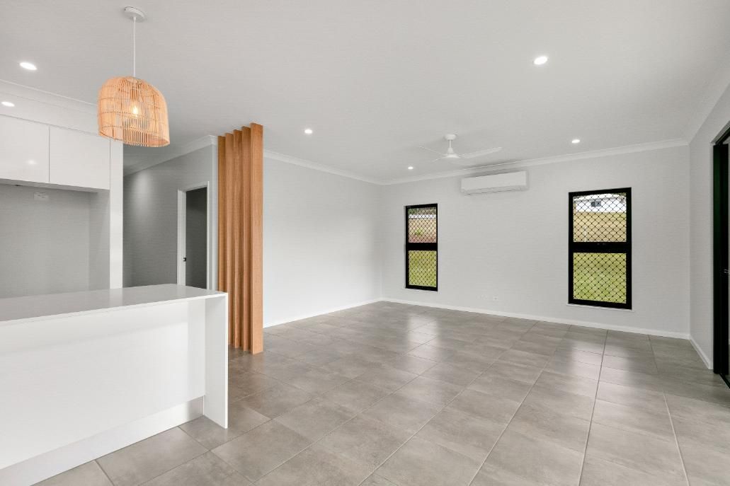 An Empty Living Room With a Tiled Floor and Two Windows — Ashlee Jones Homes in Gordonvale, QLD