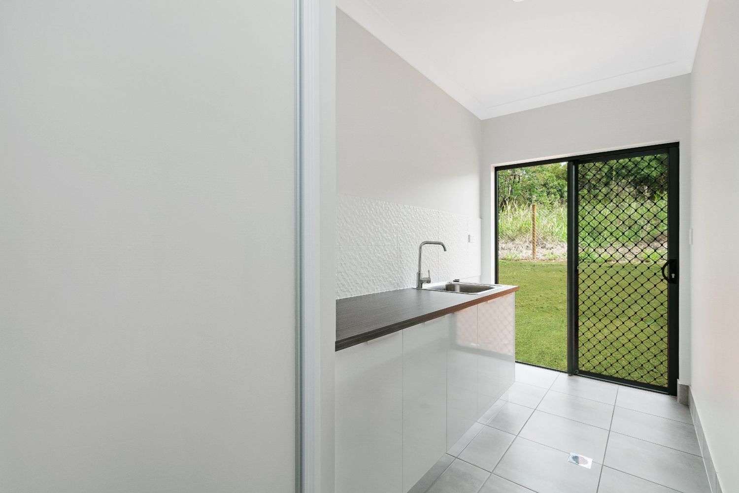 A Kitchen With a Sink and a Sliding Glass Door — Ashlee Jones Homes in Gordonvale, QLD