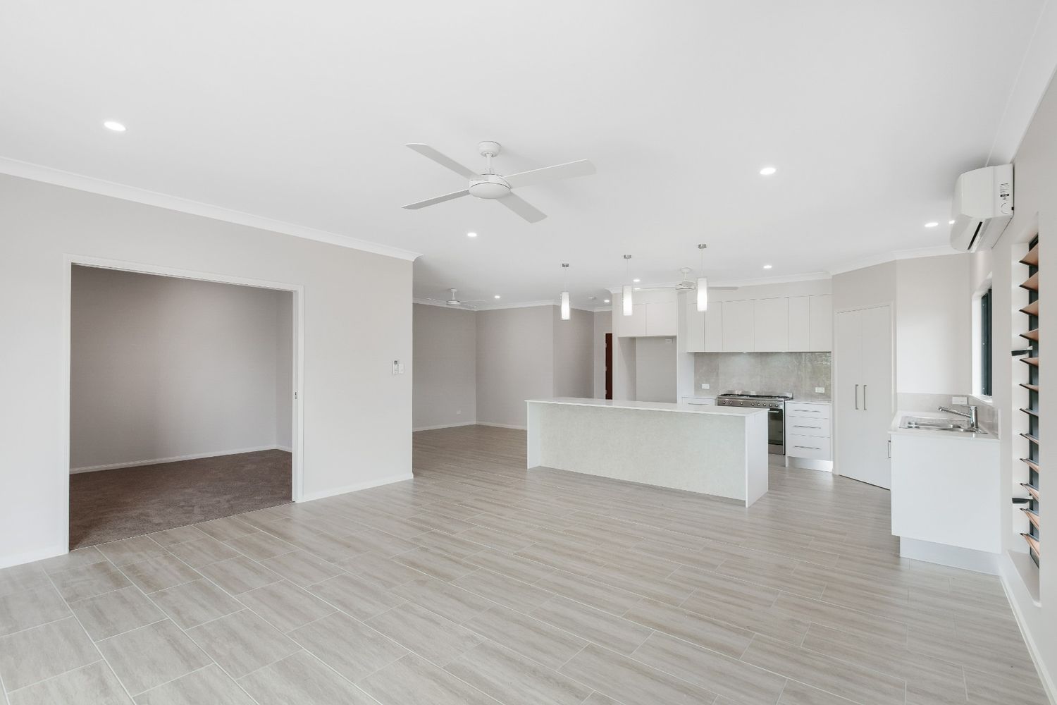 An Empty Room With a Kitchen and a Ceiling Fan — Ashlee Jones Homes in Gordonvale, QLD