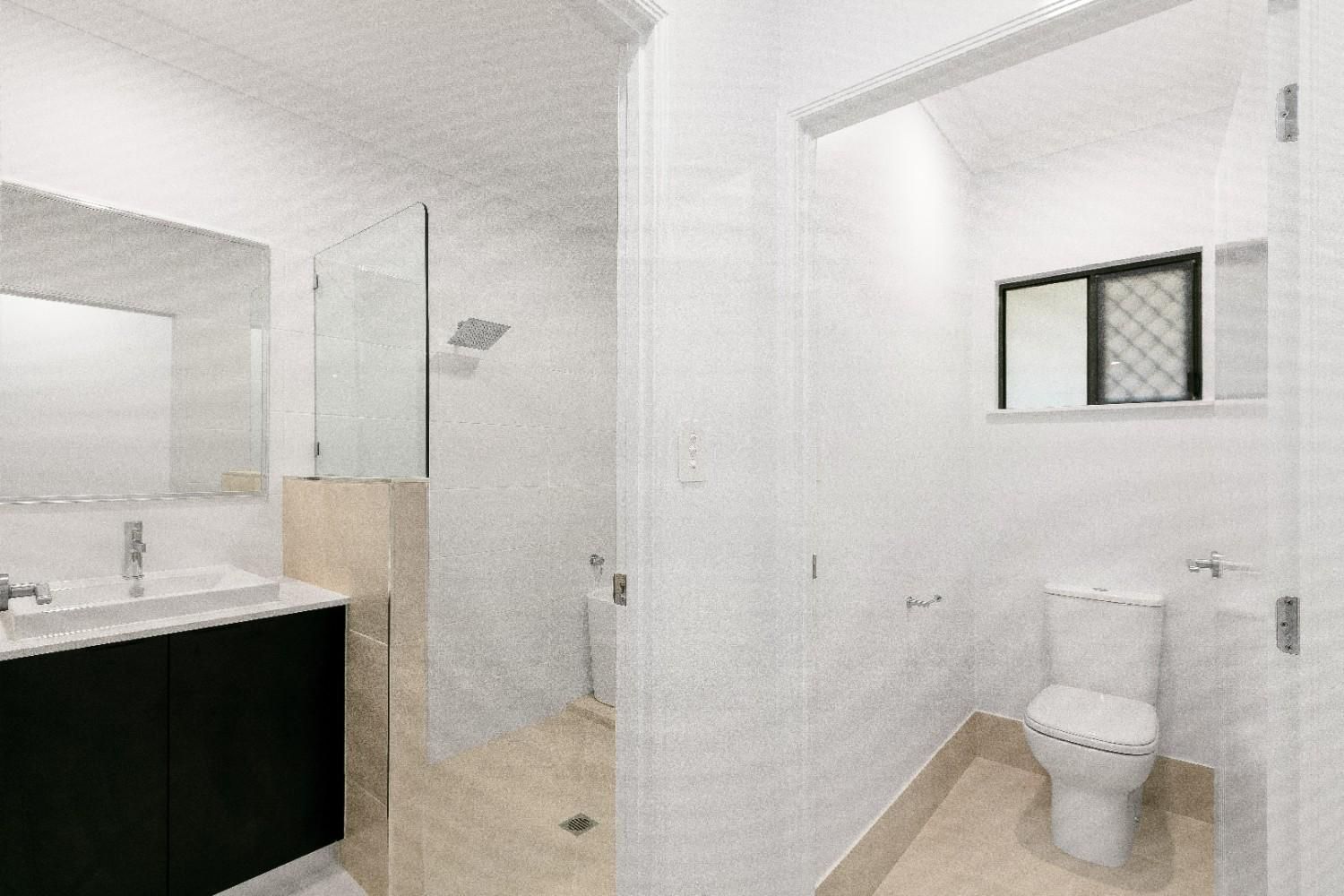 A Bathroom With a Toilet, Sink and Mirror — Ashlee Jones Homes in Gordonvale, QLD