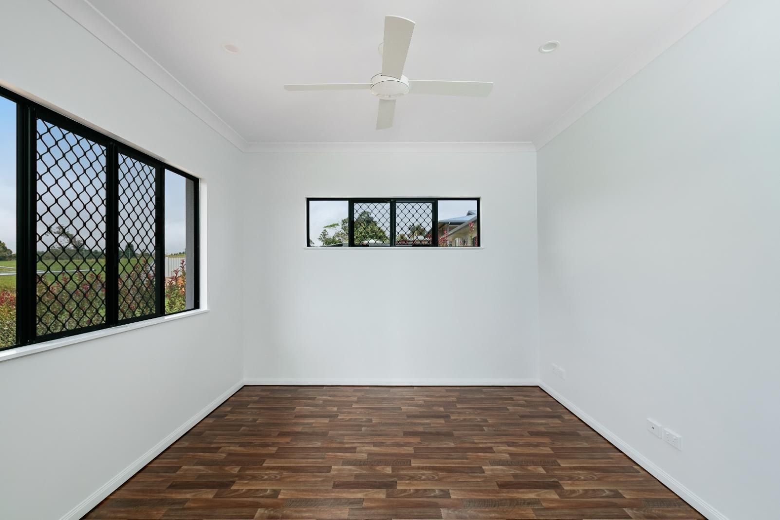 An Empty Room With a Ceiling Fan and Two Windows — Ashlee Jones Homes in Gordonvale, QLD