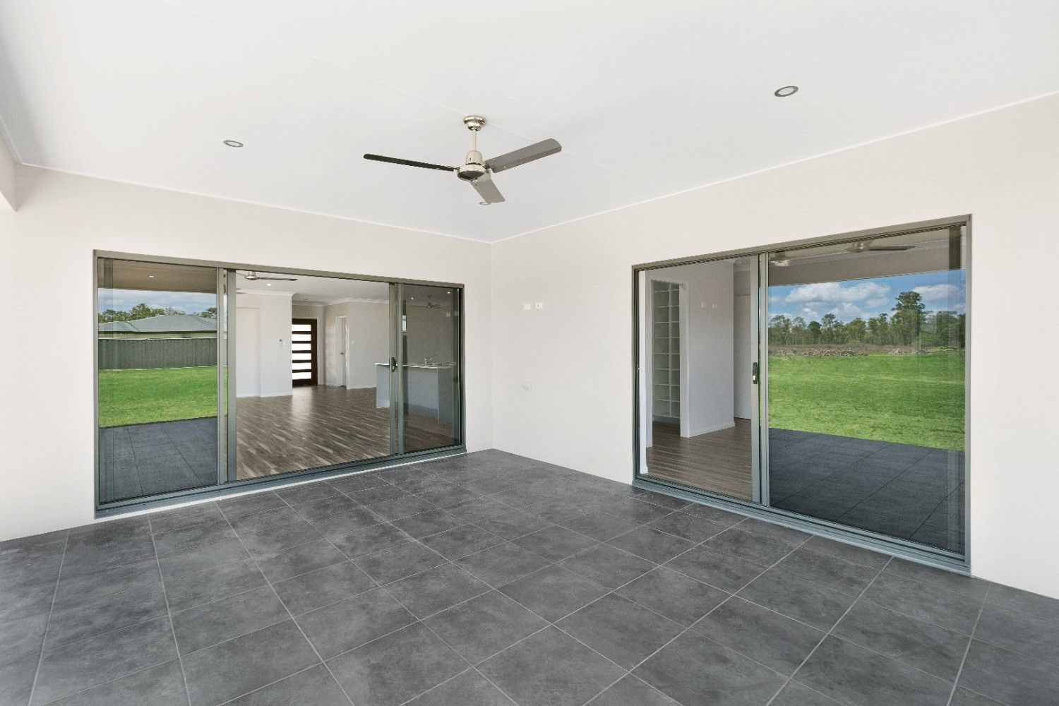 An Empty Room With Sliding Glass Doors and a Ceiling Fan — Ashlee Jones Homes in Gordonvale, QLD