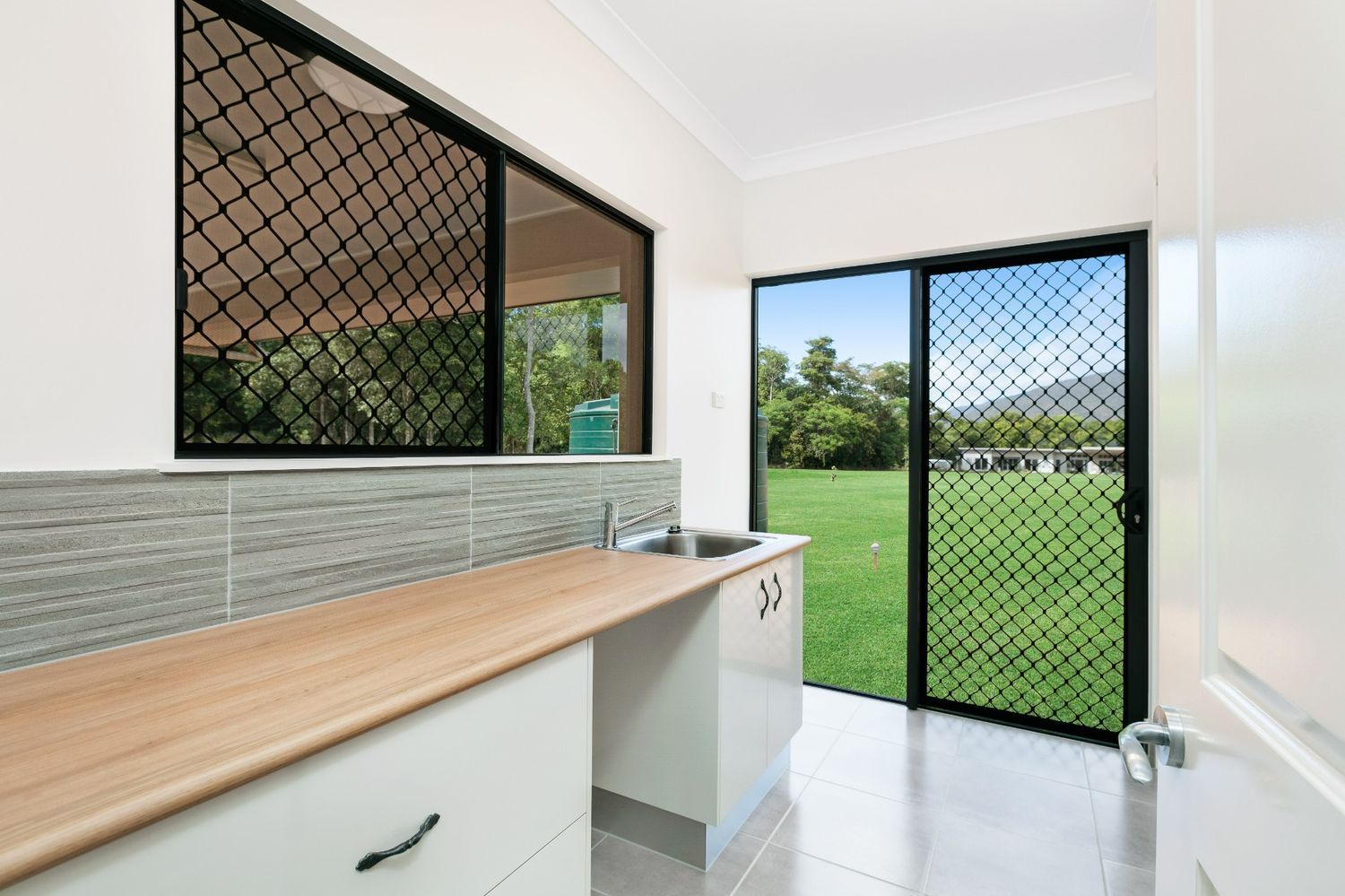 A Kitchen With a Sink and a Sliding Glass Door — Ashlee Jones Homes in Gordonvale, QLD