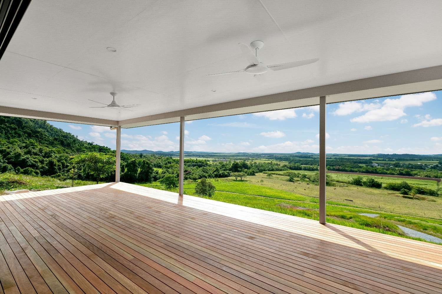 A Large Wooden Deck With a View of a Lush Green Field — Ashlee Jones Homes in Gordonvale, QLD