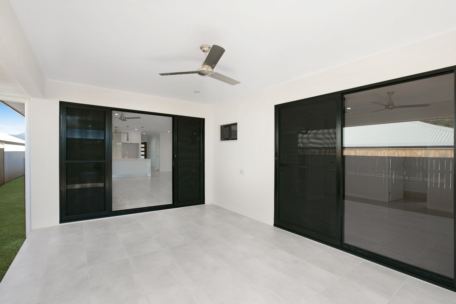 A Large Empty Room With a Tiled Floor and Sliding Glass Doors — Ashlee Jones Homes in Gordonvale, QLD