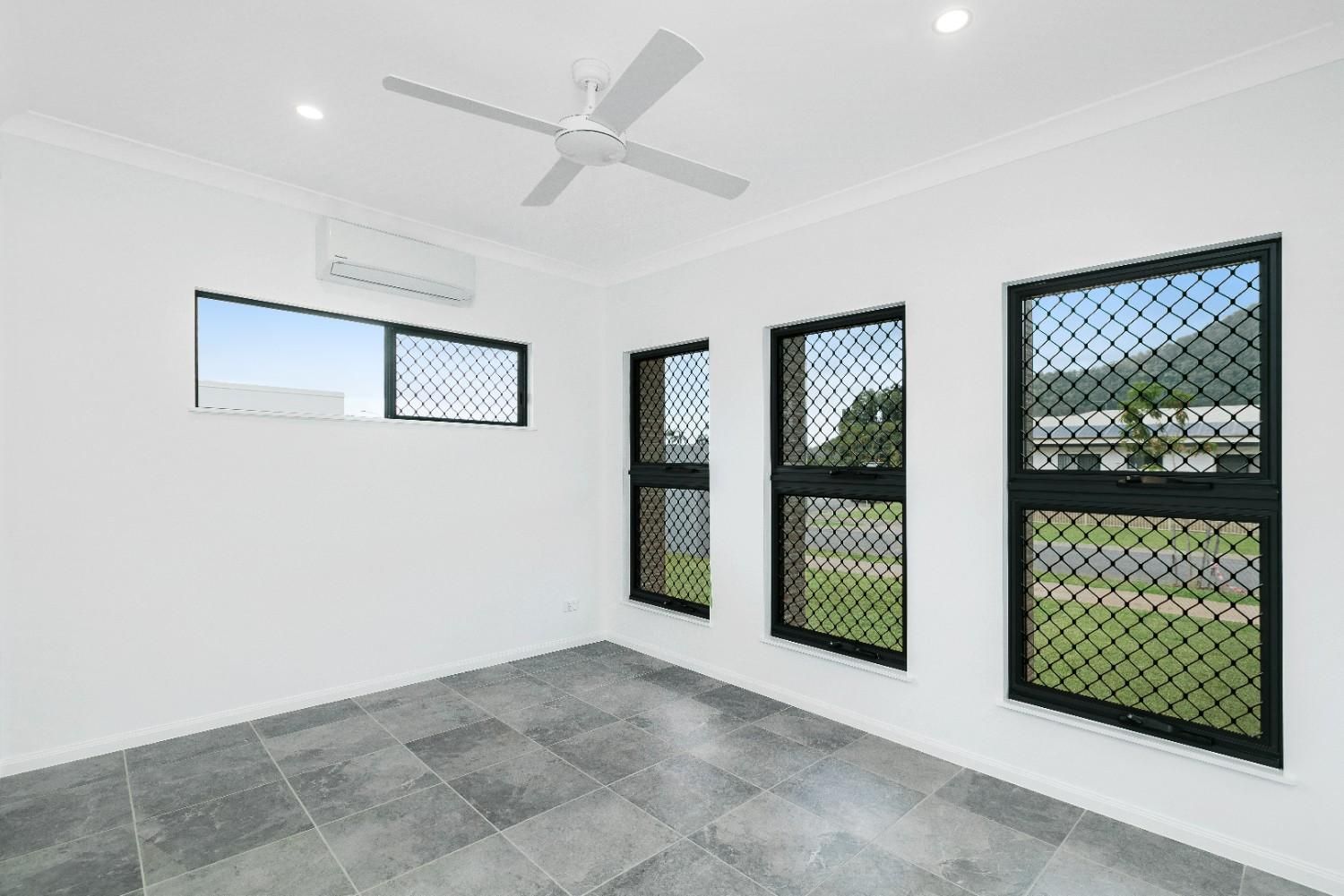 An Empty Room With Three Windows and a Ceiling Fan — Ashlee Jones Homes in Gordonvale, QLD