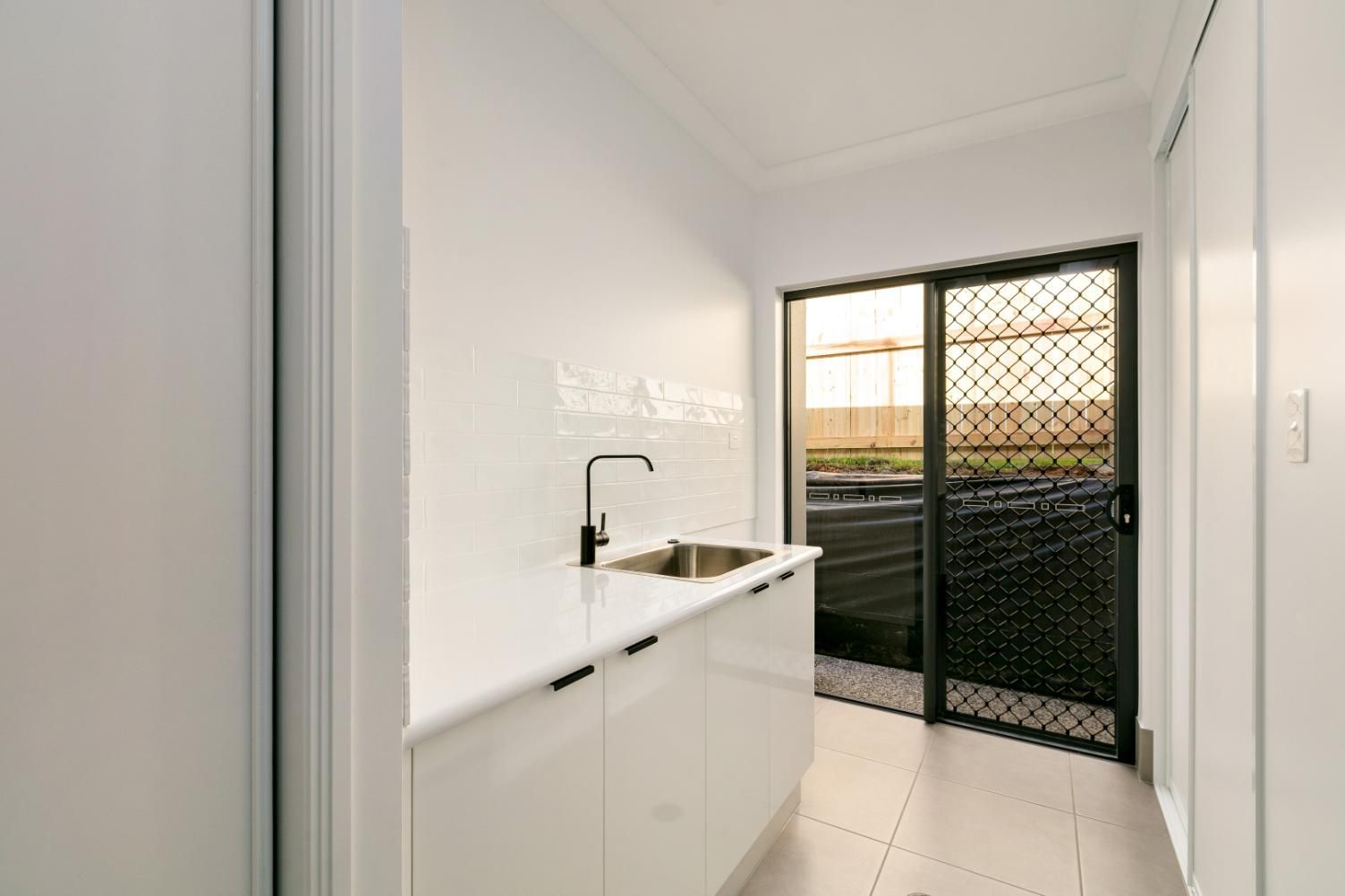 A Kitchen With a Sink and a Sliding Glass Door — Ashlee Jones Homes in Gordonvale, QLD