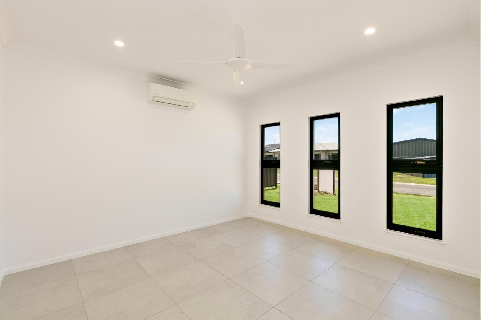An Empty Room With Three Windows and a Ceiling Fan — Ashlee Jones Homes in Gordonvale, QLD