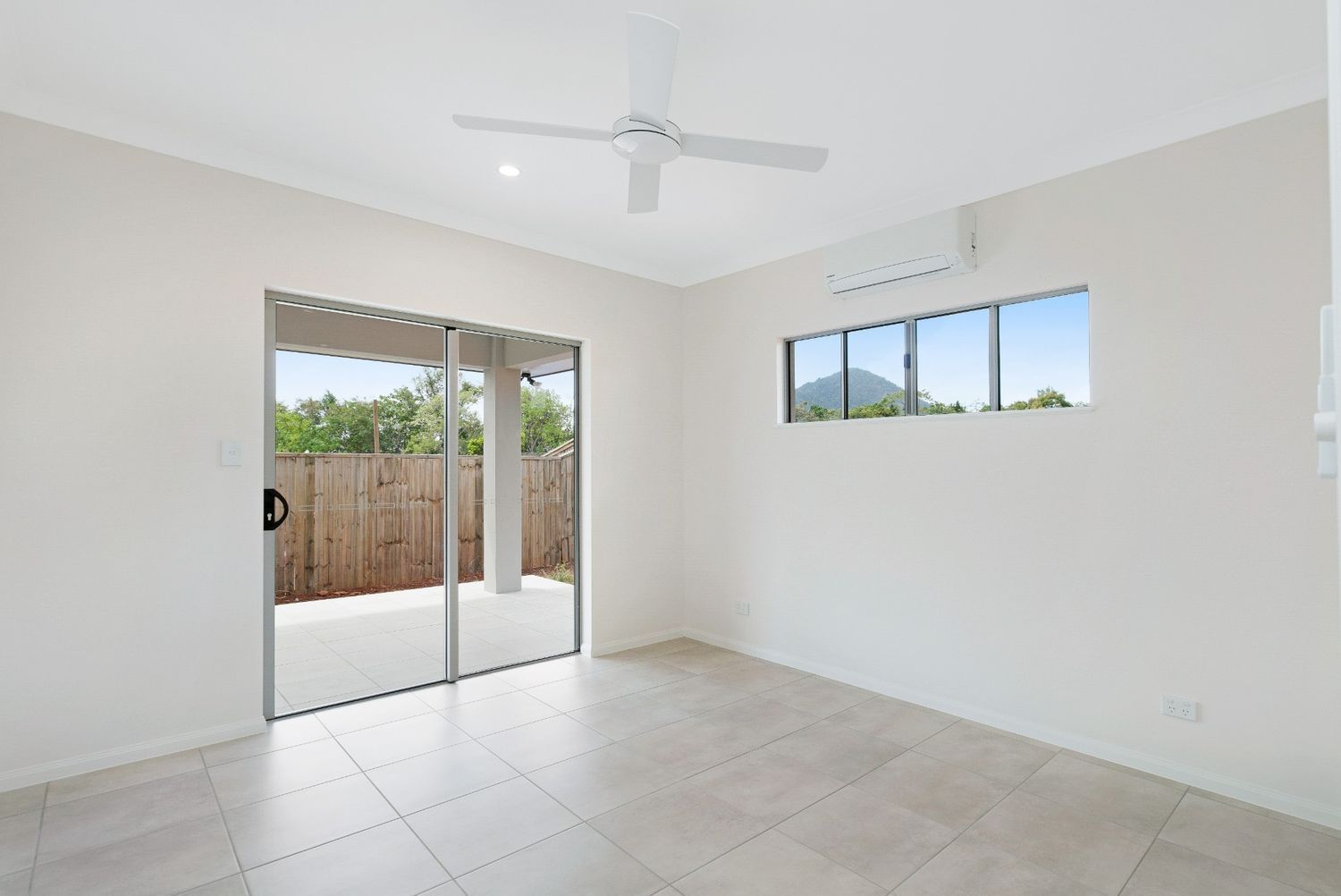 An Empty Room With a Ceiling Fan and Sliding Glass Doors — Ashlee Jones Homes in Gordonvale, QLD