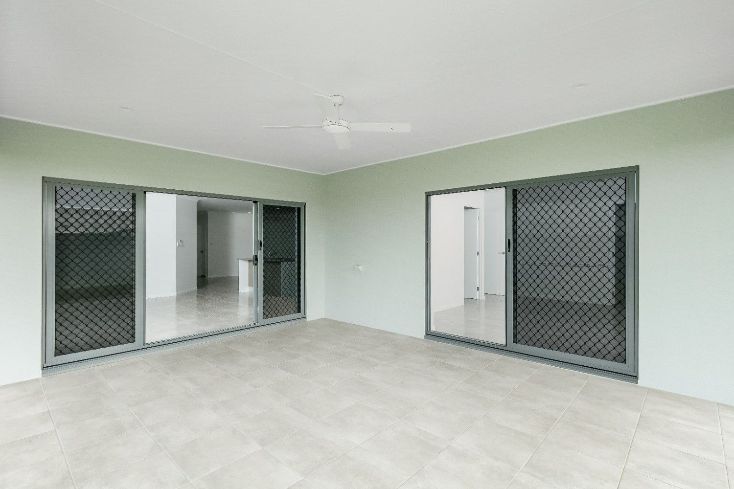 An Empty Room With Sliding Glass Doors and a Ceiling Fan — Ashlee Jones Homes in Gordonvale, QLD