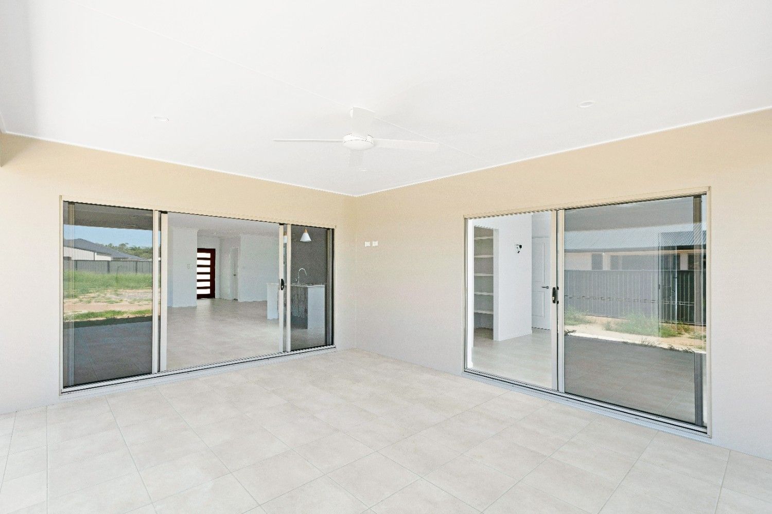 An Empty Room With Sliding Glass Doors and a Ceiling Fan — Ashlee Jones Homes in Gordonvale, QLD