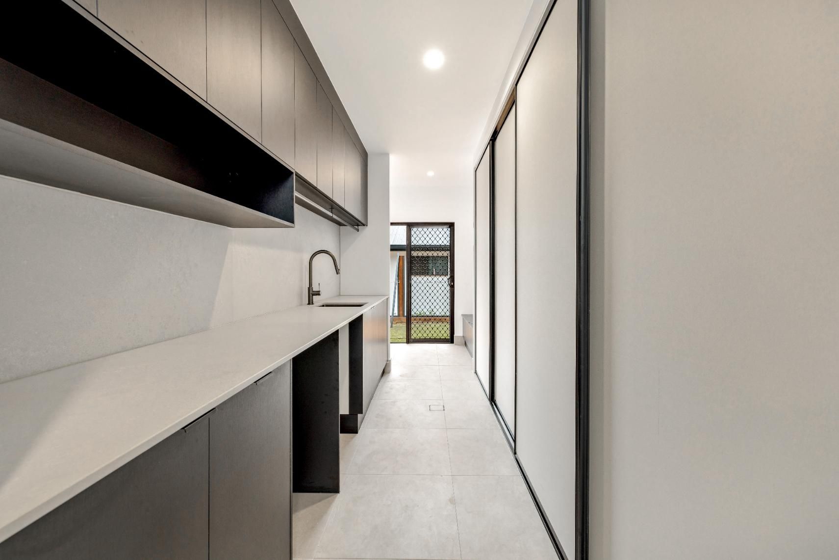 A Long Hallway with A Sink and Cabinets in A Kitchen — Ashlee Jones Homes in Gordonvale, QLD