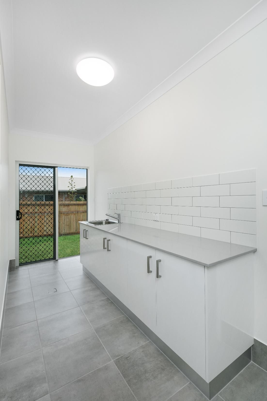 An Empty Kitchen With White Cabinets and a Sink — Ashlee Jones Homes in Gordonvale, QLD