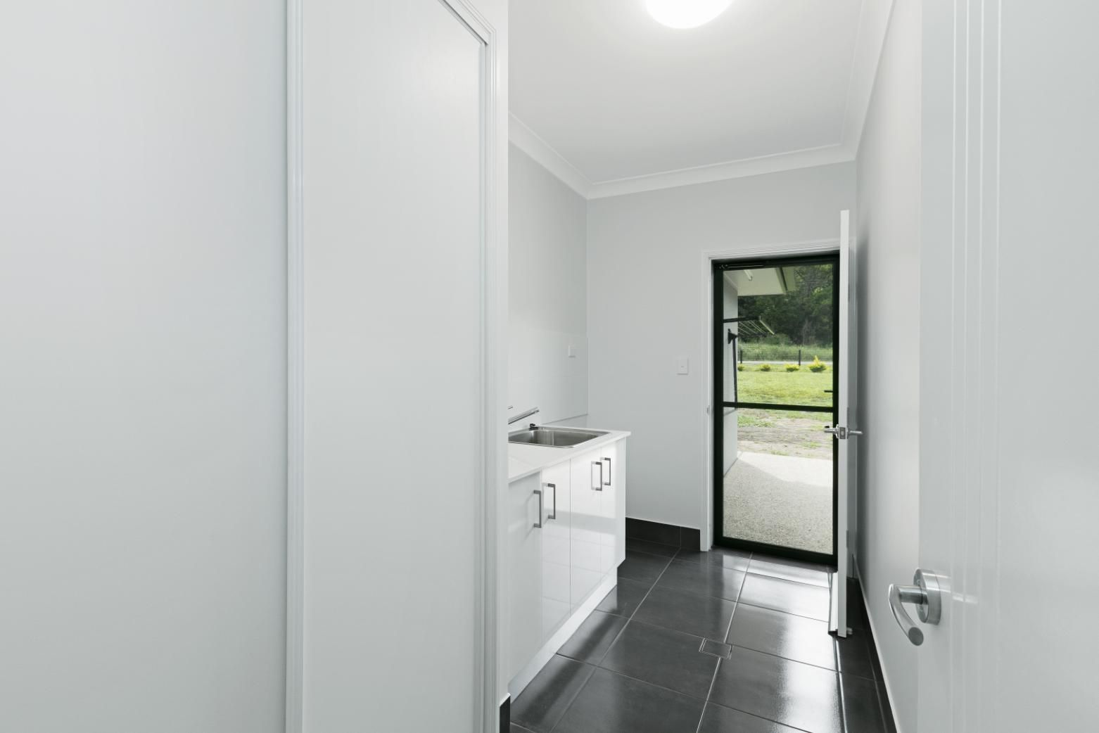 A Laundry Room With a Sink, Cabinets, and a Door — Ashlee Jones Homes in Gordonvale, QLD