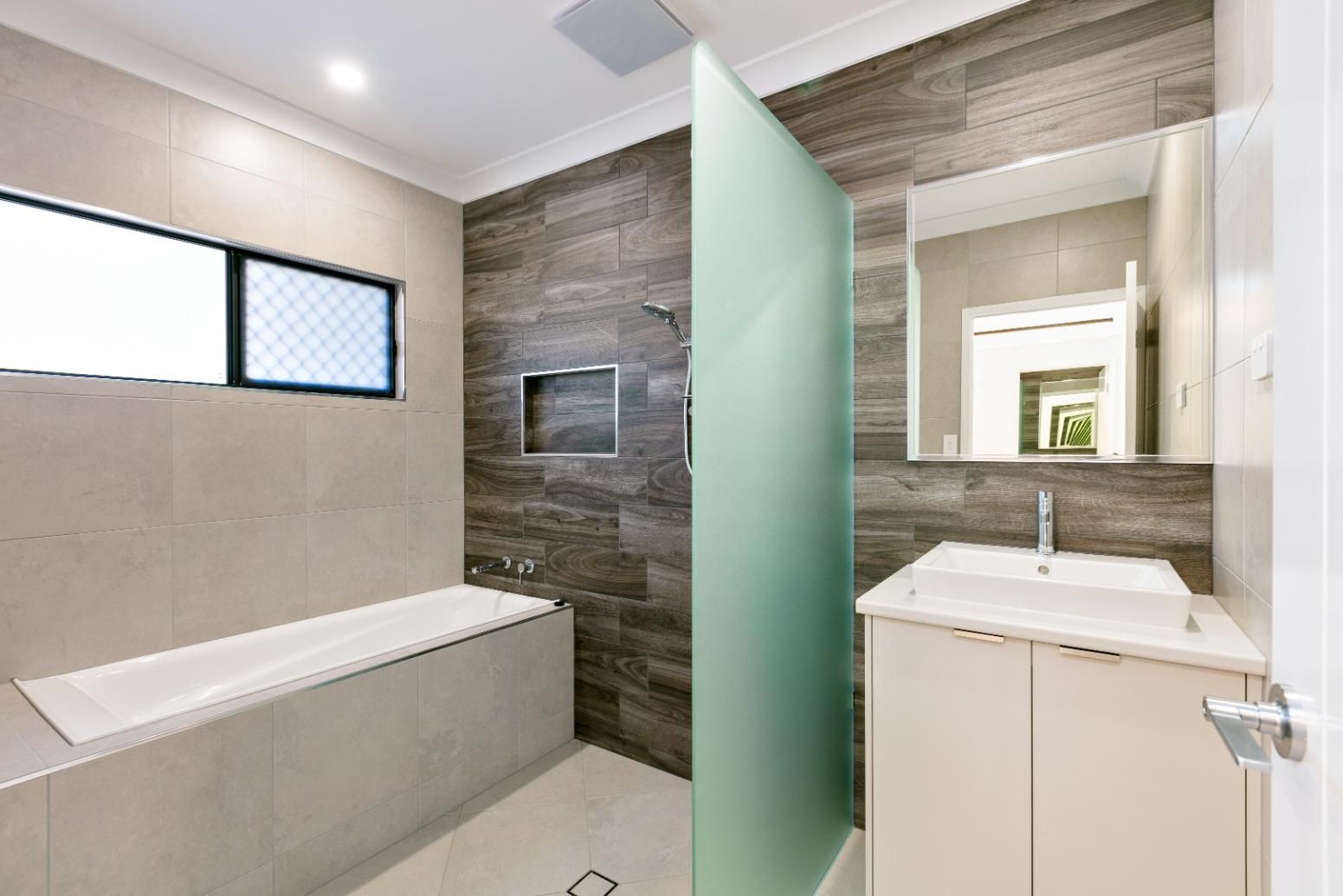 A Bathroom With a Tub, Sink, Mirror and Shower — Ashlee Jones Homes in Gordonvale, QLD