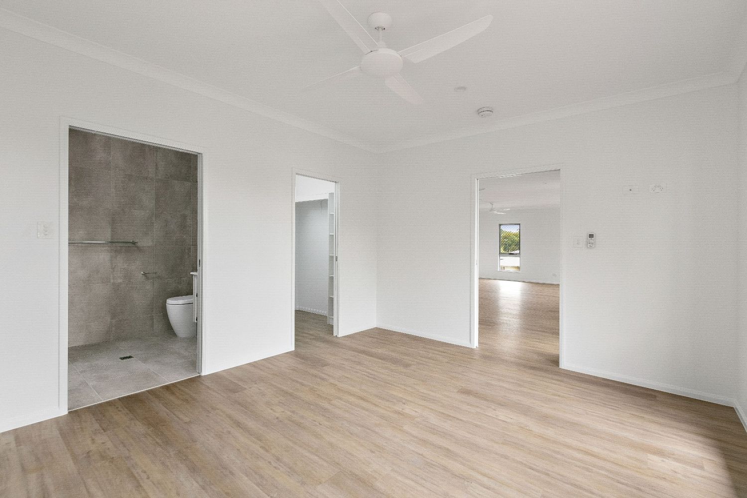 A Large Empty Room With Hardwood Floors and a Ceiling Fan — Ashlee Jones Homes in Gordonvale, QLD
